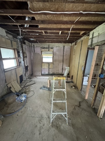 Bedroom before renovation with exposed ceiling and walls