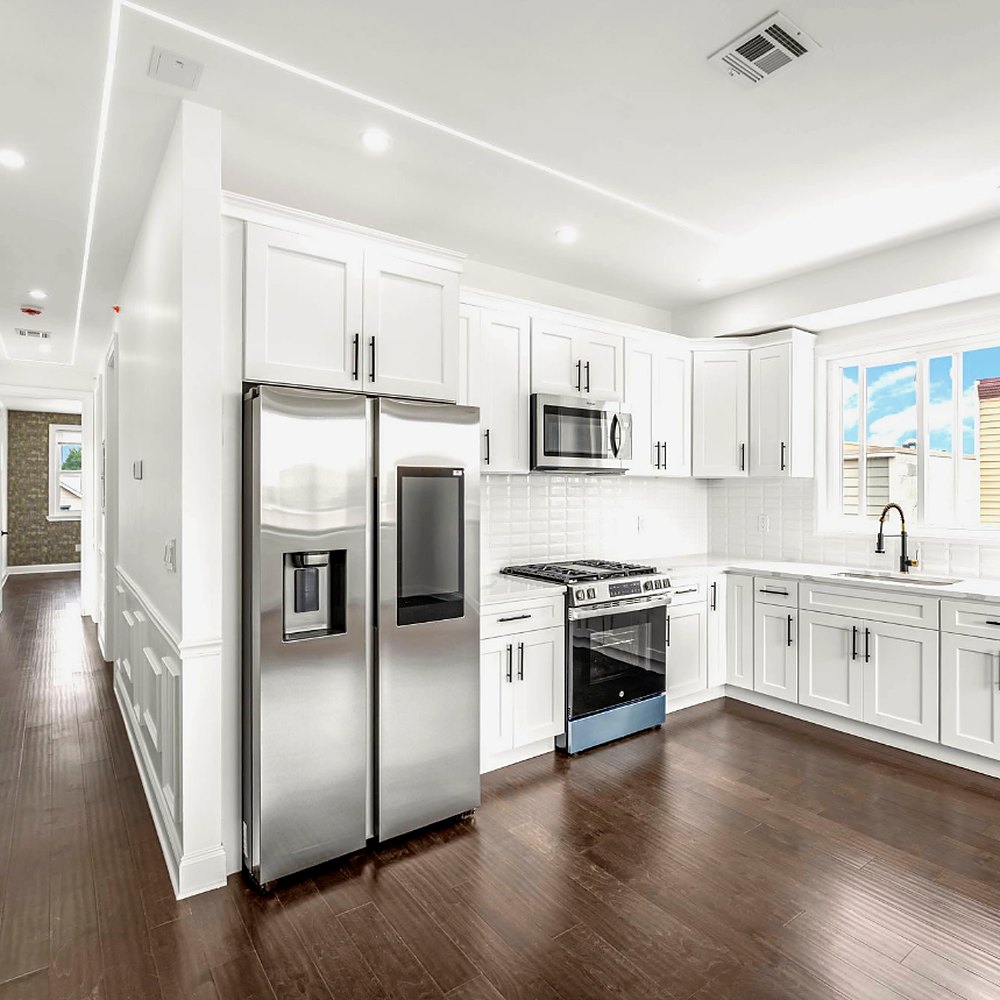 Renovated kitchen with white cabinets, stone counters and stainless appliances